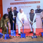 Dignitaries in formal wear using blue shovels to dig soil during a groundbreaking ceremony for a 3D chip plant in Odisha.