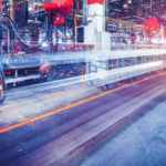 Factory assembly line with red machinery and blurred light trails featuring a Lenovo logo for India AI manufacturing