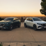 Front view of the 2026 Mercedes-Benz GLE SUV in Polar White and GLE Coupé in Emerald Green parked together during sunset.