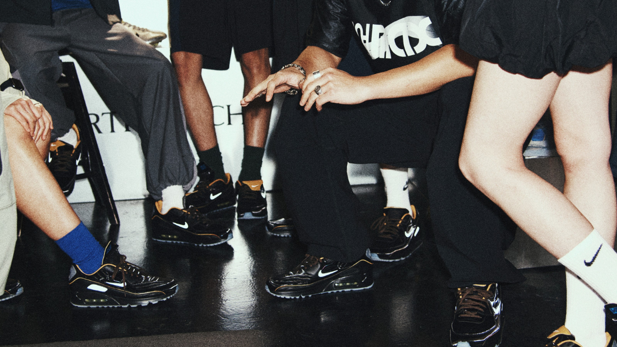 A group of people in an urban setting focusing on their feet wearing black and gold Total 90 Laser-inspired Air Max 90 sneakers.