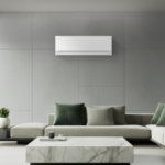 Minimalist white Samsung Bespoke AI WindFree Pro air conditioner wall-mounted above a grey L-shaped sofa in a modern luxury living room with a cityscape and bay view.