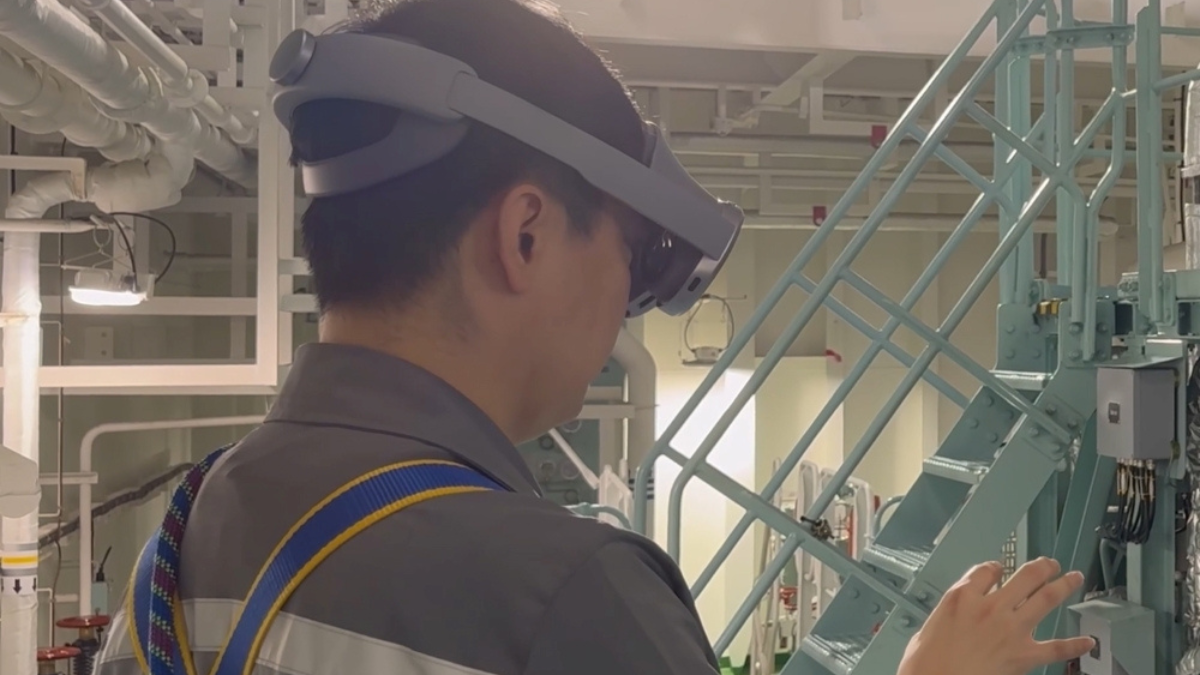 A professional in an industrial facility wearing the Galaxy XR headset to interact with spatial data and equipment panels on a factory floor.