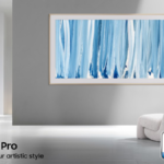 Samsung The Frame Pro TV displaying blue abstract art on a gallery wall with a TÜV Rheinland Product Carbon Reduction CO2 certification badge in the foreground.