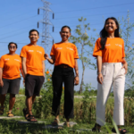 A group of young tourism entrepreneurs wearing orange TUI Care Foundation t-shirts walking along a nature path in a holiday destination.