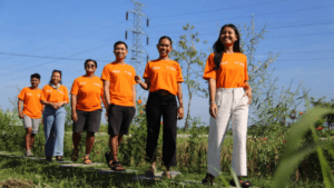 A group of young tourism entrepreneurs wearing orange TUI Care Foundation t-shirts walking along a nature path in a holida...