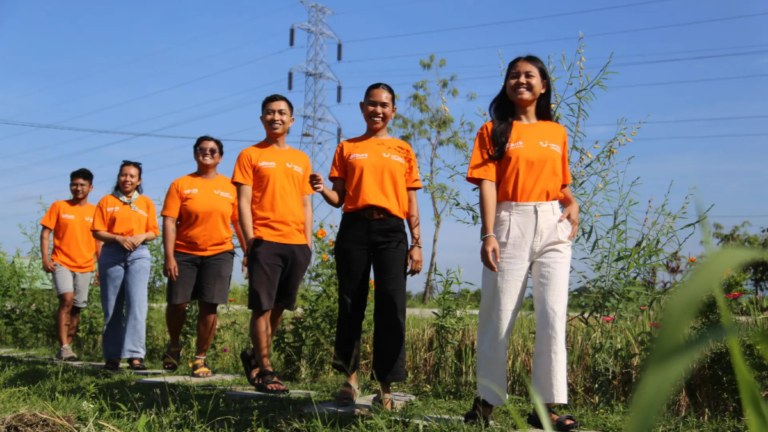 A group of young tourism entrepreneurs wearing orange TUI Care Foundation t-shirts walking along a nature path in a holiday destination.