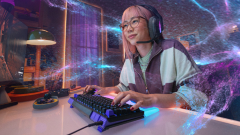 A woman with pink hair, glasses, and headset types on a Logitech G512 X keyboard with purple keycaps and a lit wrist rest,...