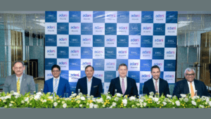 Six men in suits sit before an Adani Airports and IHG Hotels backdrop at a hospitality portfolio signing in India.