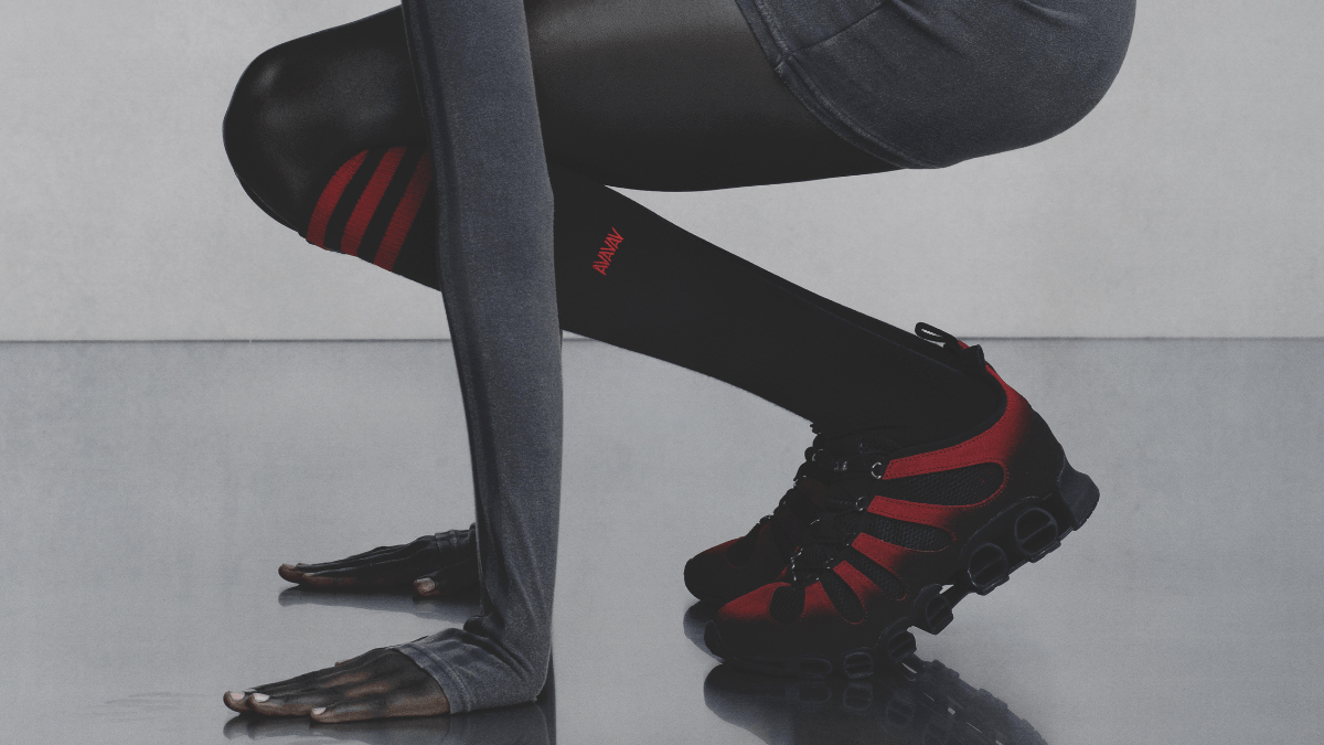 Is a raw anatomical sneaker the next big street style trend? 3 A model crouching in a grey dress and red-striped black socks featuring the red and black Avavav Megaride anatomical trainer.