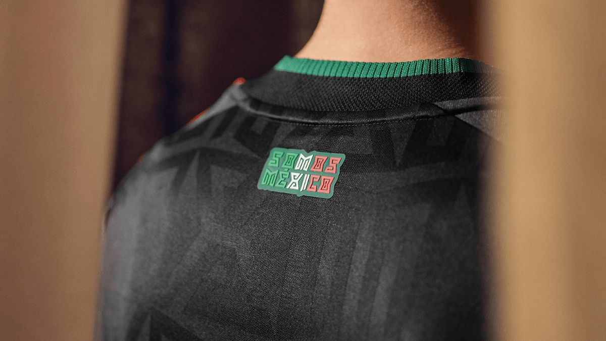 Close-up of the back of the black Mexico jersey showing the green and red "Somos México" text badge below the collar.