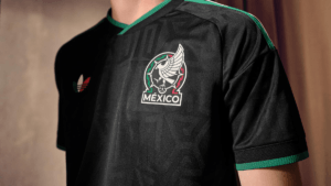 Close-up of the black adidas Mexico third jersey showing the woven national team crest and green collar accents.