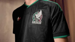 Close-up of the black adidas Mexico third jersey showing the woven national team crest and green collar accents.