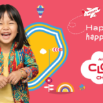 Laughing girl in patterned jacket next to cartoon graphics and the Air India Cloud Chasers logo on pink background.