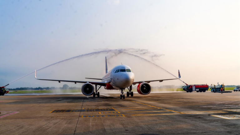 White Air India A320neo aircraft receiving a ceremonial water salute on the runway tarmac in Hanoi.