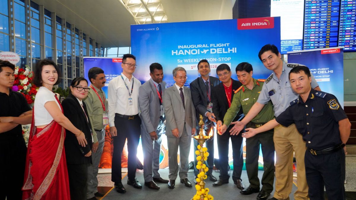 Dignitaries lighting a traditional Indian lamp in front of an Air India Hanoi to Delhi inaugural flight banner.