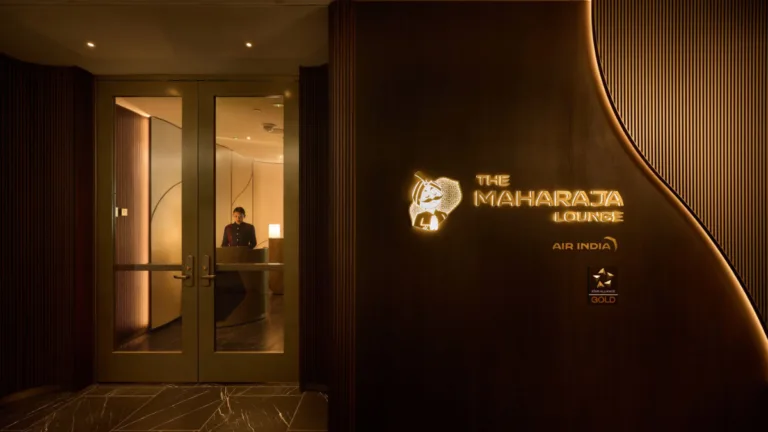 The premium upgrade that actually rewards loyal Indian flyers 2 The dark wood entrance of the Air India Maharaja Lounge at SFO featuring a glowing golden brand logo and glass doors.
