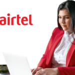 Woman in a red blazer working on a laptop with a cup of tea next to an Airtel logo, representing Secure Workforce in India.