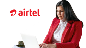 Woman in a red blazer working on a laptop with a cup of tea next to an Airtel logo, representing Secure Workforce in India.