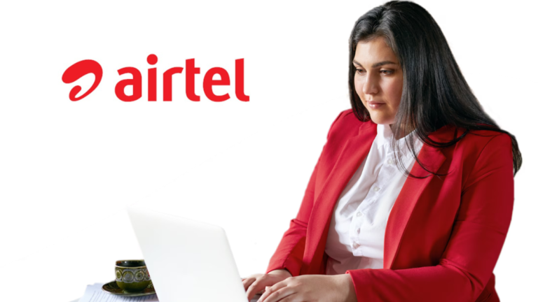 Woman in a red blazer working on a laptop with a cup of tea next to an Airtel logo, representing Secure Workforce in India.