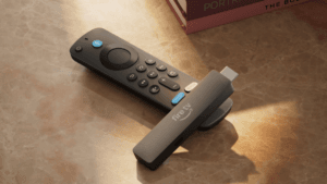 Amazon Fire TV Stick dongle resting on its voice remote on a sunlit marble table, representing the new India launch.