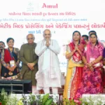 Amit Shah, Bhupendra Patel, and women cooperative leaders on stage at the Madhur Dairy plant launch in India.