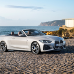 A silver BMW convertible with brown leather seats parked on cobblestones by the sea in India, an exclusive CBU import.