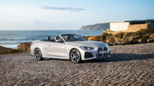 A silver BMW convertible with brown leather seats parked on cobblestones by the sea in India, an exclusive CBU import.