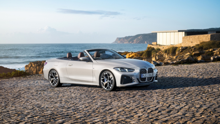A silver BMW convertible with brown leather seats parked on cobblestones by the sea in India, an exclusive CBU import.