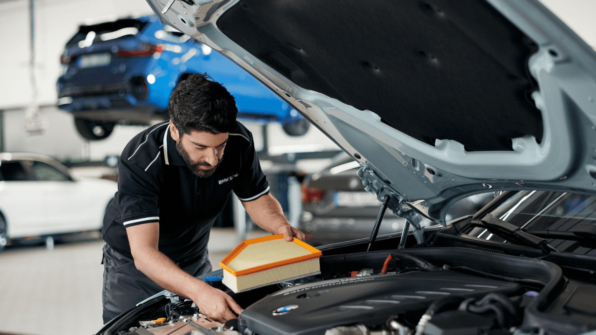 Is your luxury car ready for the intense Indian summer? 1 A mechanic inspecting an orange-bordered air filter under the open bonnet of a car during a BMW India service check.