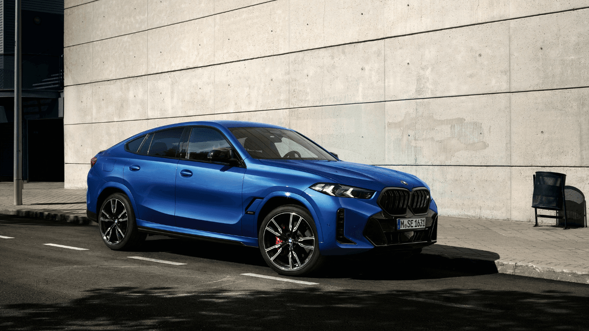 The imported V8 coupe built for urban expressways 1 A blue BMW X6 M60i xDrive parked against a concrete wall, highlighting its sweeping aerodynamic roofline for India.