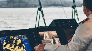 Officer watching maritime monitoring screens on a ship bridge, highlighting the Indian-developed command software.