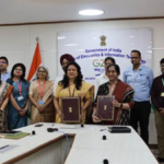 Representatives from IndiaAI and ICMR holding signed documents in a MeitY office setting for healthcare collaboration