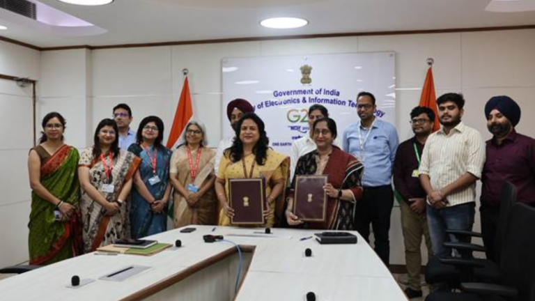 Representatives from IndiaAI and ICMR holding signed documents in a MeitY office setting for healthcare collaboration
