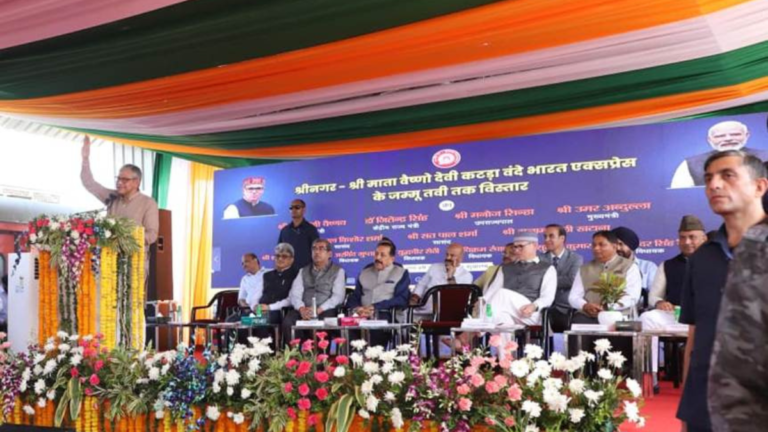 Ashwini Vaishnaw waves from a flower-decked podium during the Vande Bharat extension event on a stage in Jammu.