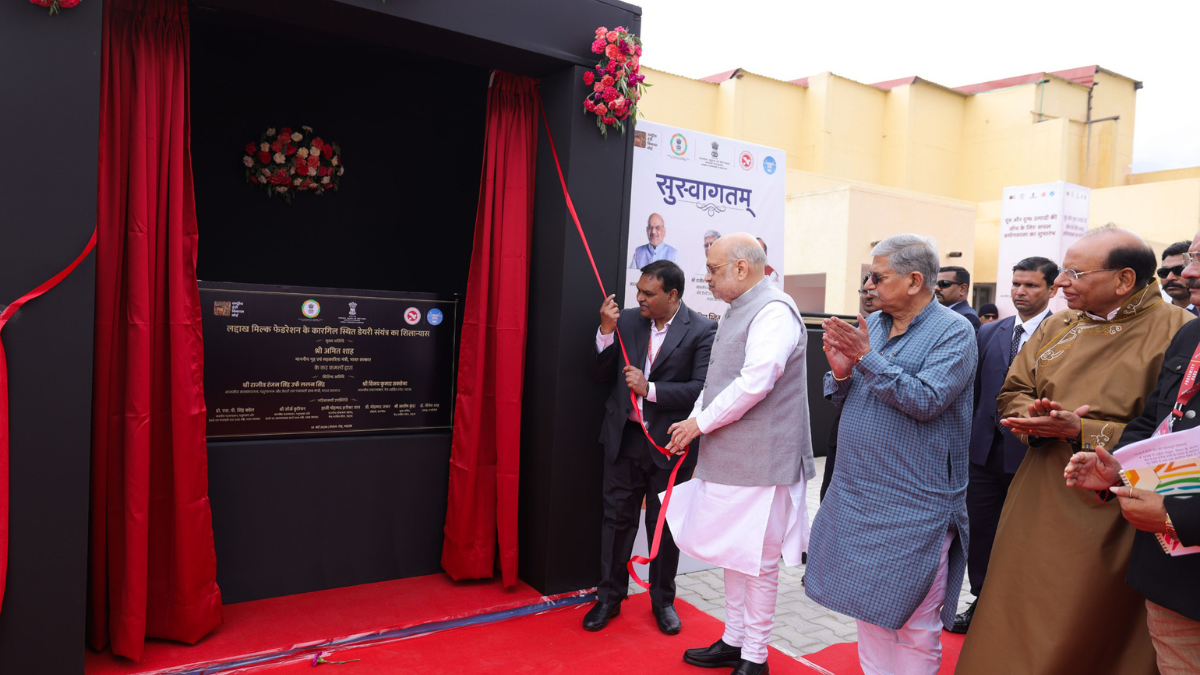 Shri Amit Shah pulling a red ribbon to reveal a foundation stone plaque for a dairy plant in Kargil Ladakh.