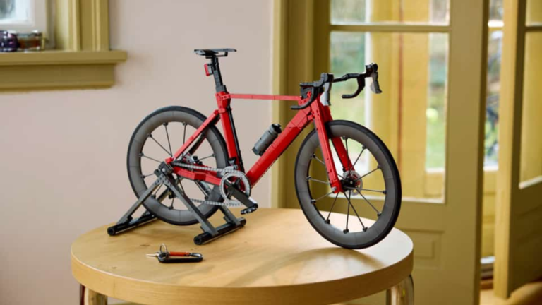 Red LEGO Icons Road Bike on a black display stand over a wooden table with functional drivetrain details