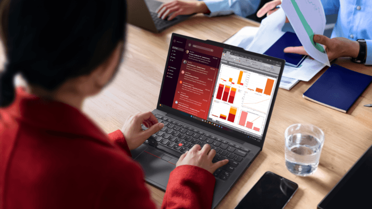 This new business laptop weighs just 0.93kg 2 A woman in a red jacket uses a ThinkPad laptop showing data charts in a collaborative Mumbai office setting.