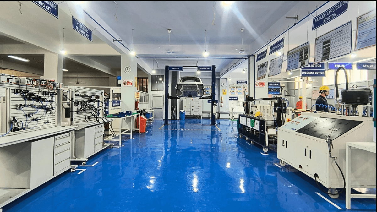 The new manufacturing lab fast-tracking factory careers 2 A clean technical training lab with blue floors featuring pneumatic stations and a car chassis on a lift in Rohtak, India.