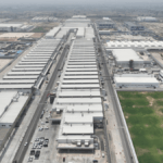 Aerial view of the massive white industrial buildings and parking lots at the Maruti Suzuki Kharkhoda manufacturing facili...