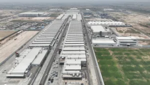 Aerial view of the massive white industrial buildings and parking lots at the Maruti Suzuki Kharkhoda manufacturing facili...