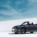 Dark grey MINI Convertible parked with the roof down against a white wall under a blue sky, showcasing the new India launch.