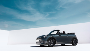 Dark grey MINI Convertible parked with the roof down against a white wall under a blue sky, showcasing the new India launch.