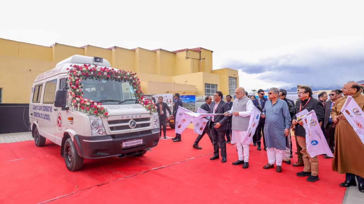 Shri Amit Shah flagging off a white mobile laboratory van decorated with flowers in Ladakh.