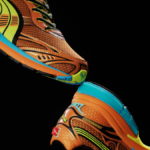 PUMA Homura runner in orange and yellow with PUMALITE cushioning and turquoise accents on a black background.
