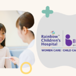 Smiling girl in pink shirt interacting with a doctor beside Rainbow Hospital and BirthRight logos in Bengaluru.