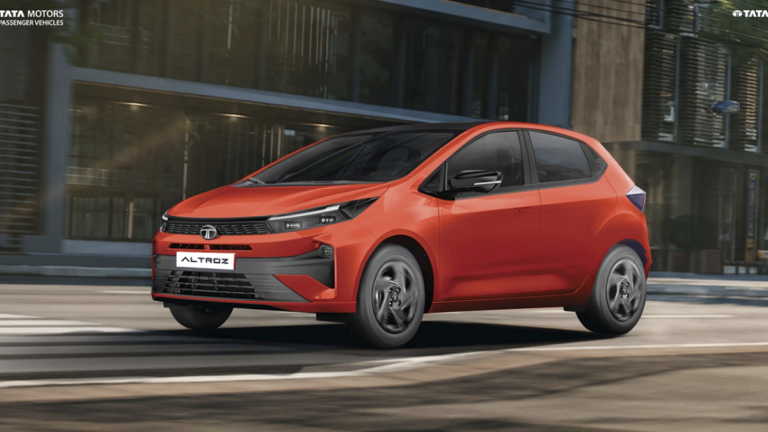 This ₹8.70L car is India’s first automatic CNG hatchback 1 Red Tata Altroz hatchback driving along a city street with modern buildings showcasing its premium design.