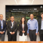 Seven professionals standing before a digital screen announcing Cooling-as-a-Service for Intellion Park in Chennai.