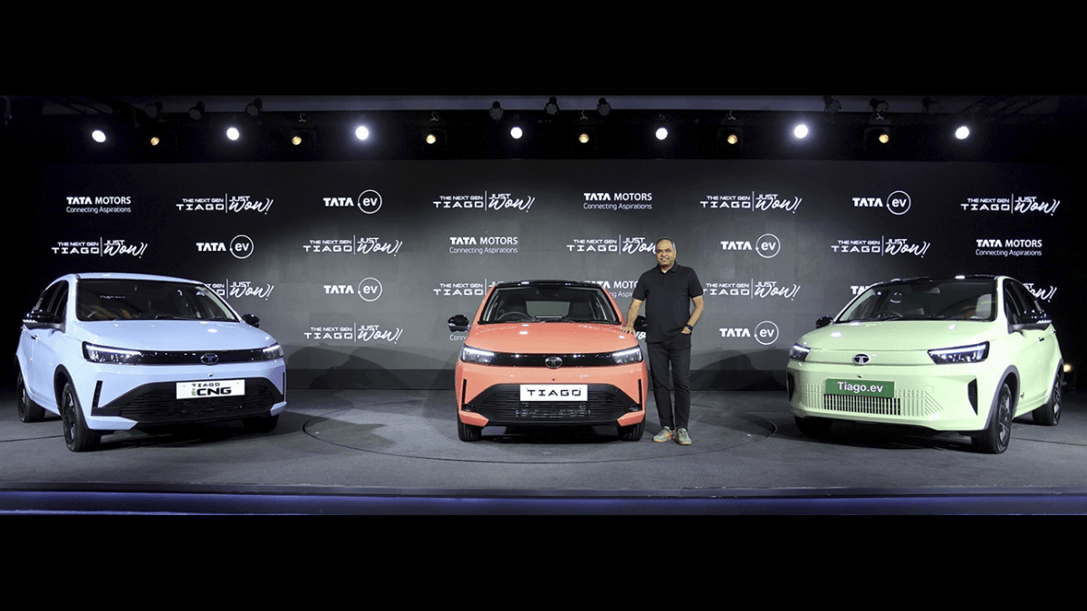 Tighter stage shot of three men standing with the iCNG, Petrol, and Tiago.ev models during an India launch event.