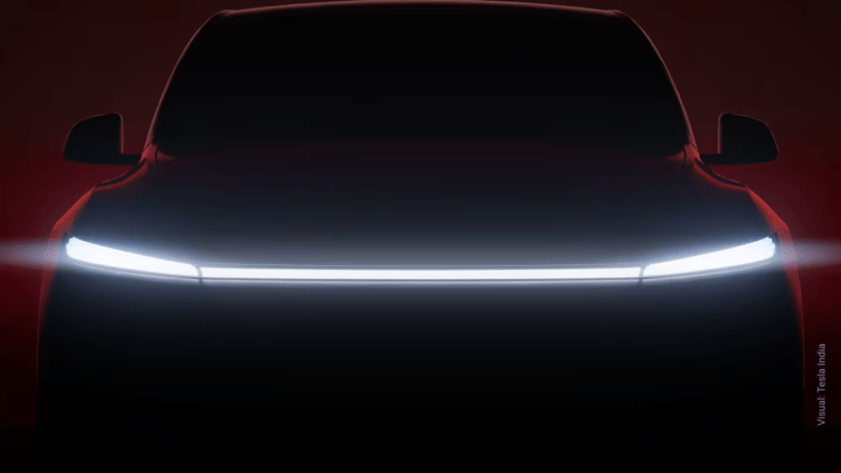 Does a third row justify the premium for the new extended Model Y? 4 Dark silhouette of a Tesla SUV facing forward with a single, continuous white LED light bar illuminated across its front end.