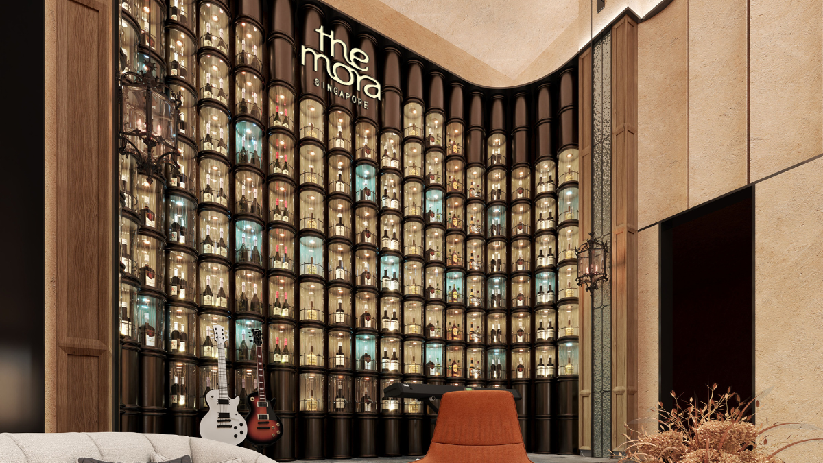 Curved wall of illuminated bottle capsules behind two electric guitars and an orange chair in a designer bar.